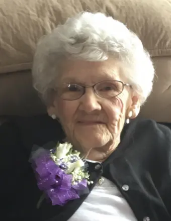 An old person with glasses and a purple flower

Description automatically generated