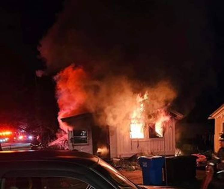 A house on fire at night

Description automatically generated