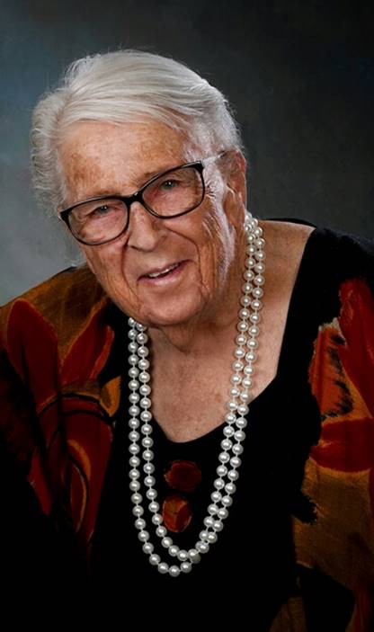An old person wearing glasses and a pearl necklace

Description automatically generated