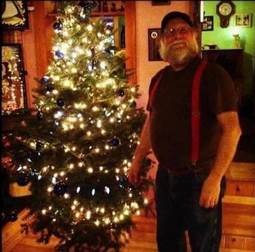 A person standing next to a christmas tree

Description automatically generated