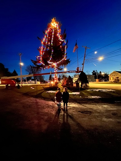 Two people standing in front of a christmas tree

Description automatically generated