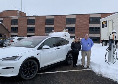 A person and person standing next to a white car

Description automatically generated