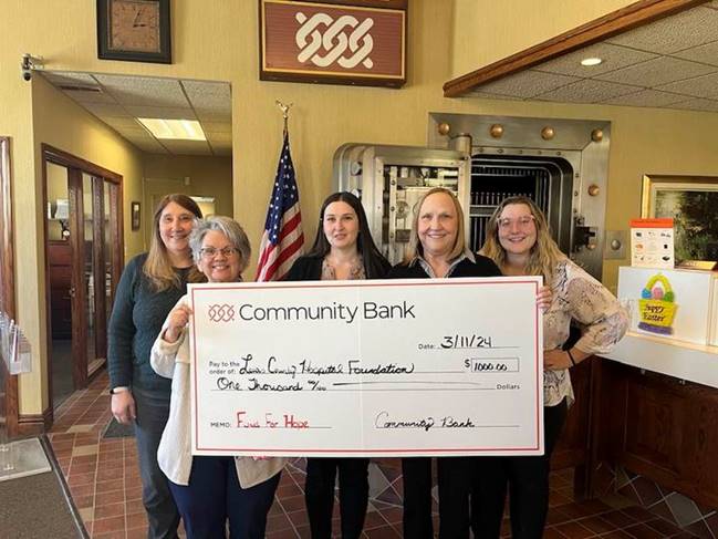 A group of people holding a large check

Description automatically generated
