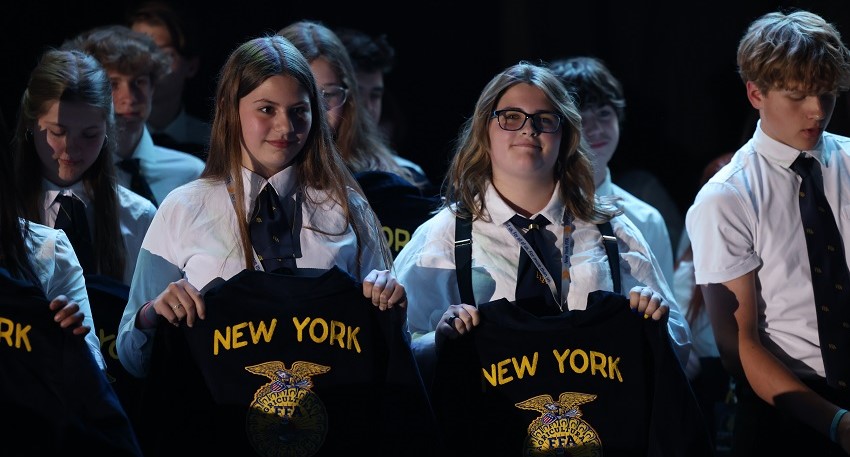 A group of girls holding up shirts
Description automatically generated