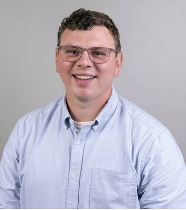 A person wearing glasses and a blue shirt

Description automatically generated
