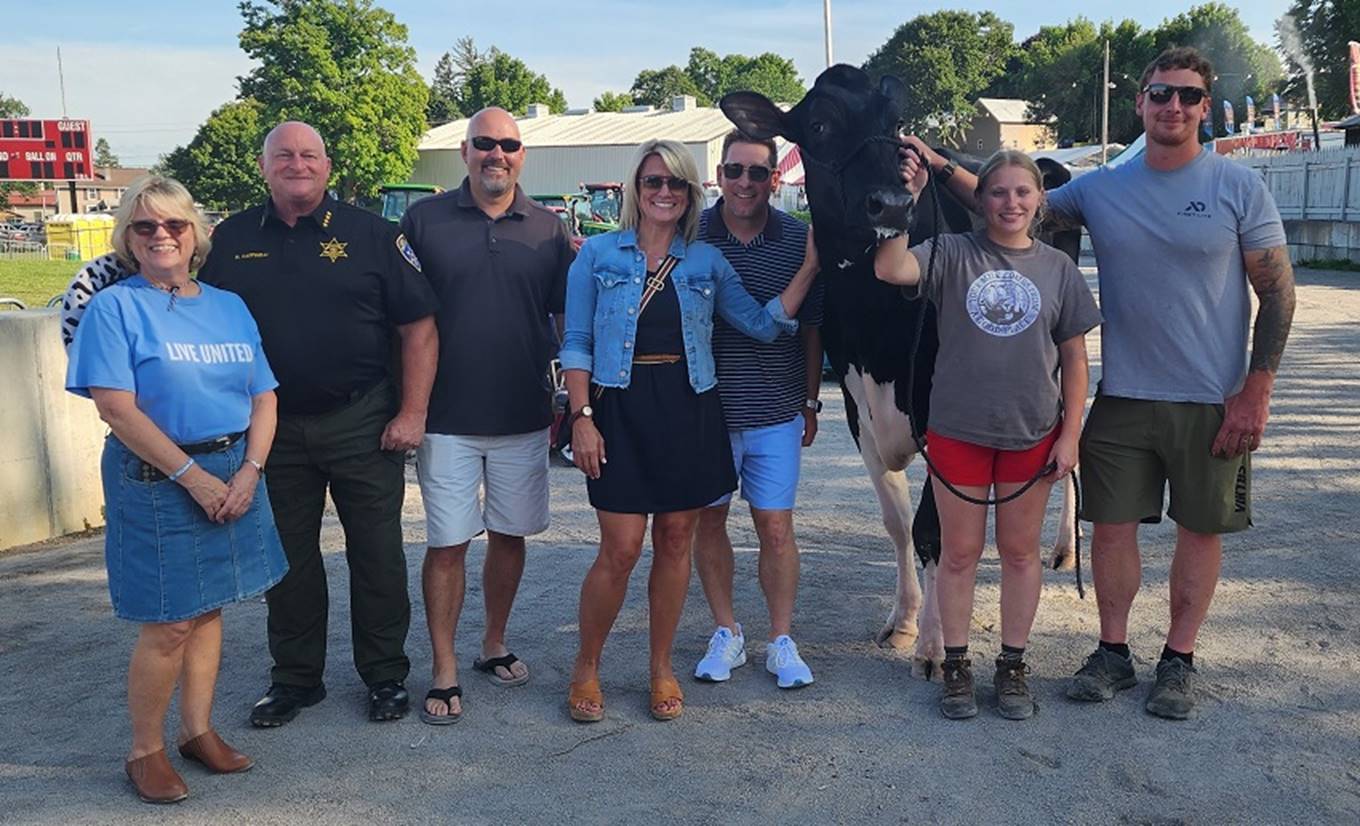 A group of people standing next to a cow

Description automatically generated