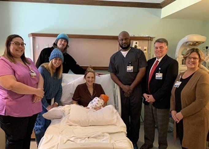 A group of people standing around a person in a hospital bed

Description automatically generated