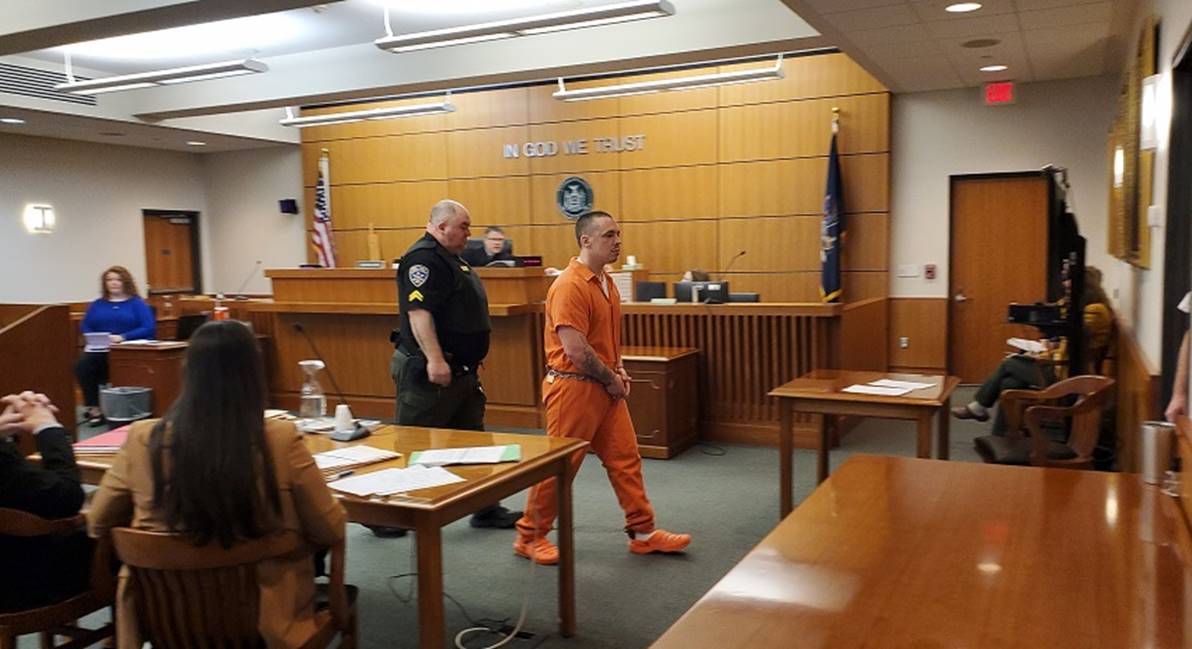 A person in orange jumpsuit walking in a courtroom

AI-generated content may be incorrect.